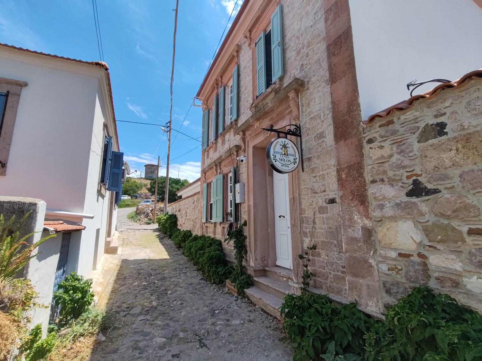Cunda Milos'un arnavut kaldırımlı sokaktaki taş cephesi ve yeşil panjurları