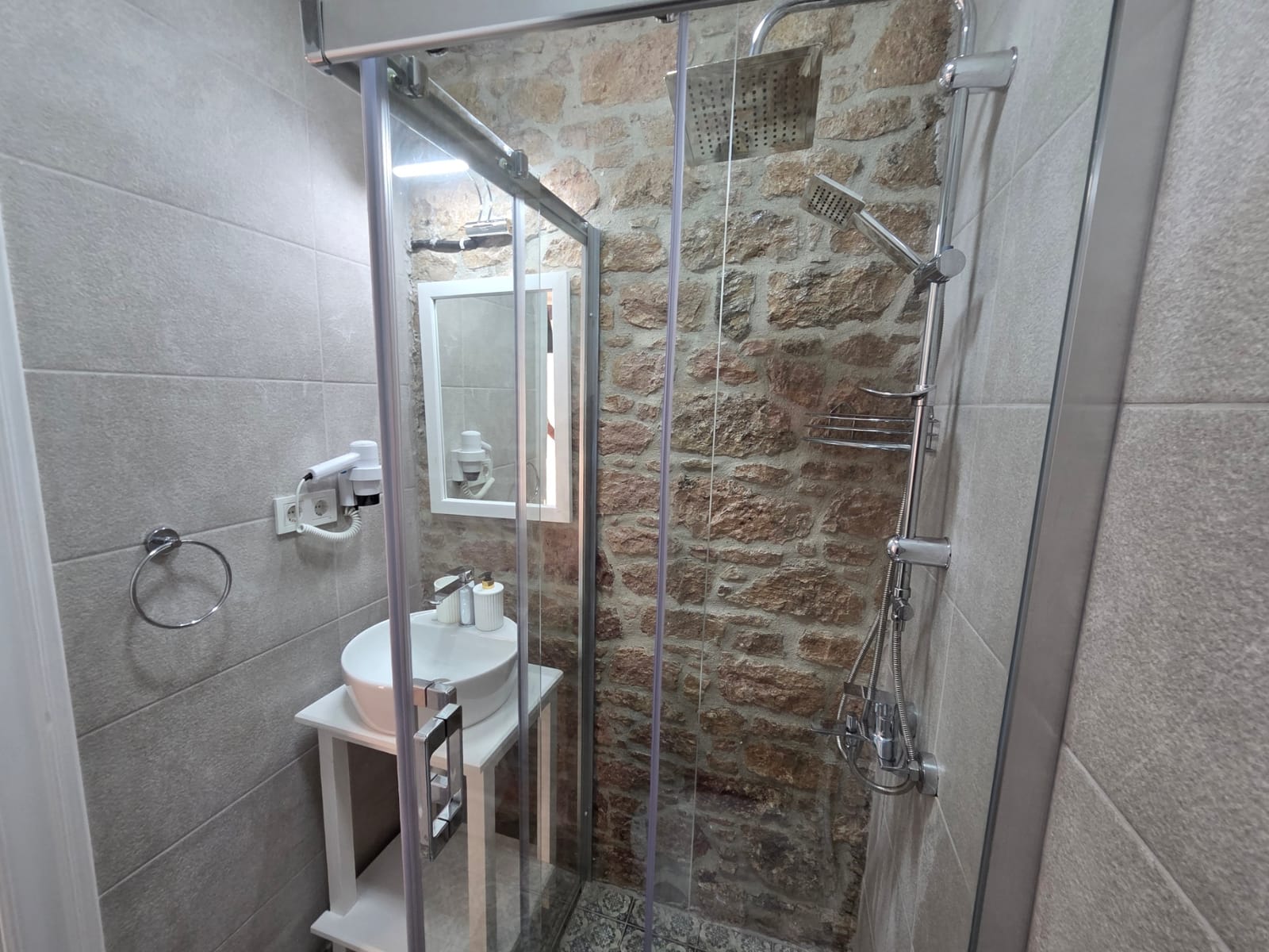 Numara 2 — taş duvarın önünde duşakabinli banyo