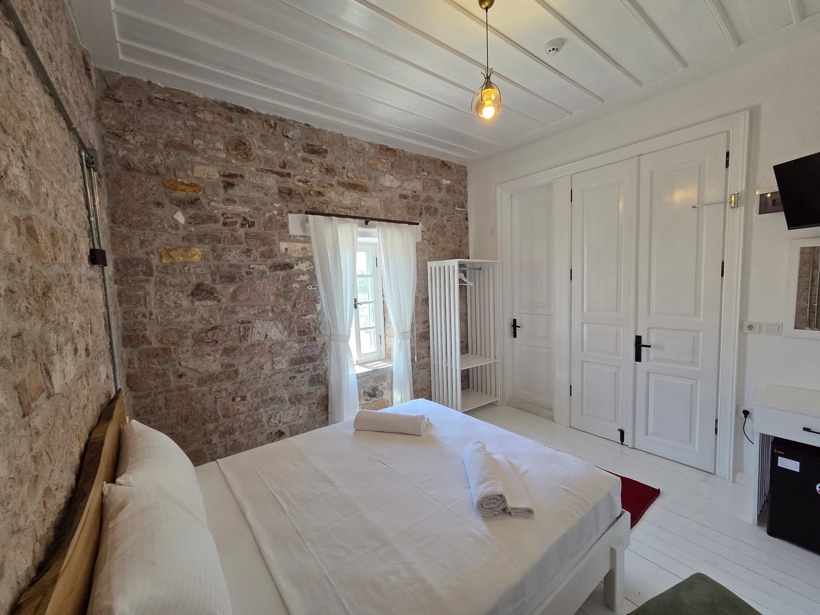 Numara 3 — boydan boya taş duvar, yüksek pencere ve çift kişilik yatak, Cunda Milos butik otel Ayvalık