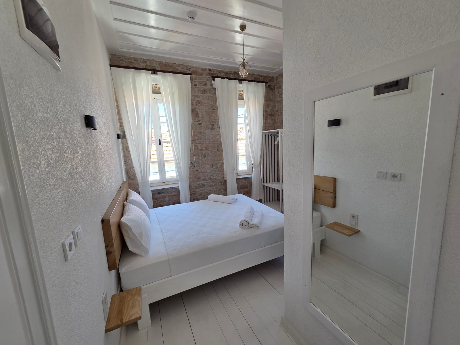 Numara 4 — iki pencereli aydınlık yatak odası ve taş duvar detayı, Cunda Milos butik otel Ayvalık